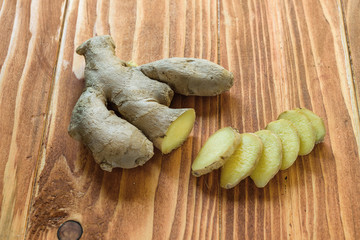 Fresh ginger root and ginger sliced on a wood table cutting board