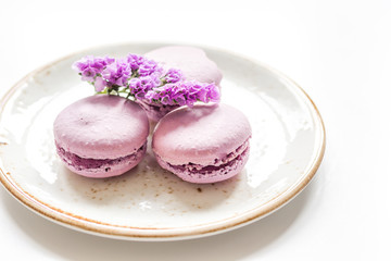 macaroons and mauve flowers for light breakfast on white desk background