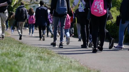 Crowd of people walking through park, slow motion
