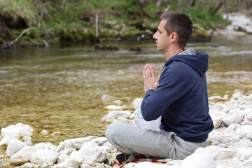 Fototapeta premium Man relaxing, doing yoga after jogging, workout in beautiful nature landscape. Sport and healhy life style concept