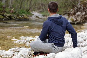 Man relaxing, doing yoga after jogging, workout in beautiful nature landscape. Sport and healhy life style concept