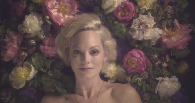 Attractive woman lies in bed of flowers