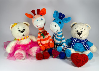 Knitted striped Orange Giraffe with a red flower, blue giraffe, white teddy bear in a pink skirt and a white teddy bear wearing a scarf with a big heart. a toy. handmade