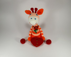 Knitted striped Orange Giraffe with a red flower with a big heart. a toy. handmade