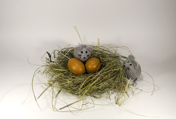 The nest of hay, dry grass red eggs and chicken knitted gray mouse.