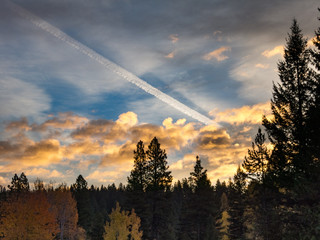 Dawn sky with low clouds and jet contrail dividing sky