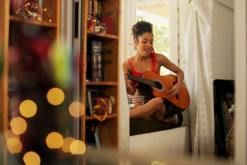 Fototapeta premium Black Woman Singing And Playing Guitar At Home