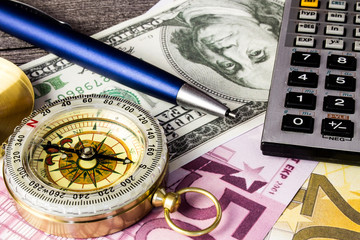 Tourist compass,calculator,banknotes and pencil on wooden table