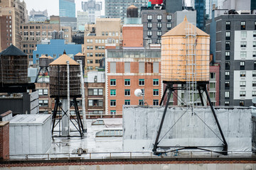 Old vintage water tanks on the roof in New York City Manhattan midtown. - obrazy, fototapety, plakaty