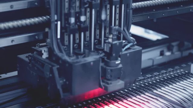 Automated Electronic circuit board production close up. Machine Printe digital board, contract manufacturing. Manufacture electronic microchips. Robotic arm. Red light. High-tech. Full HD. Blue toning