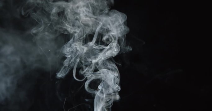 Smoke billows up into frame against black background, as if from fire