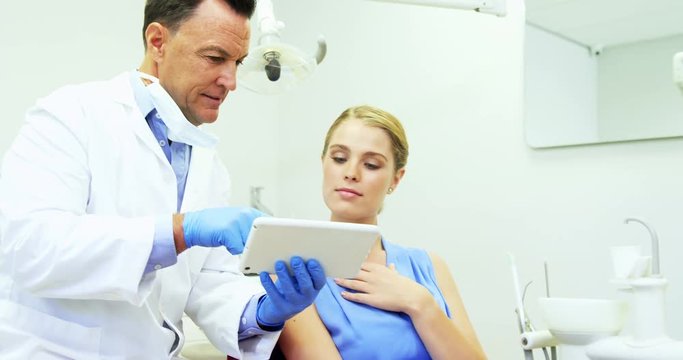 Dentist discussing over digital tablet with female patient