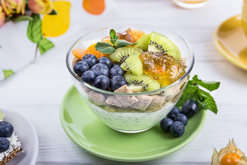Healthy breakfast. Yogurt with chia seeds, corn pads, kiwi, blueberries and physalis on a white background