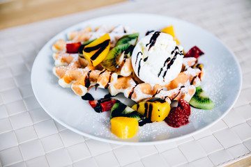 Viennese wafers with fruits: kiwi, avocado, strawberry, chocolate, ice cream, mint. Fruits cut into slices.