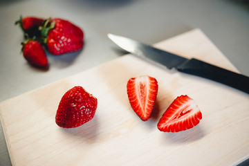 Strawberry cut with a knife on a cutting board, two halves. The concept of cooking a tasty, healthy, healthy breakfast with oatmeal.