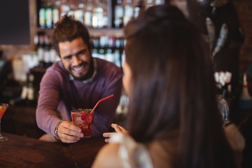 Bartender serving a cocktail drink to customer 