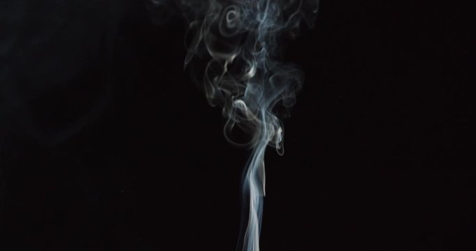 Detail of smoke columns from cigarettes against black background