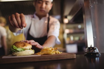 Chef placing tooth pick over burger at order station