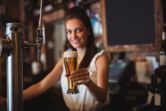Female bar tender holding glass of beer