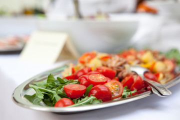 Salad of tomato greens and seafood on a white table.