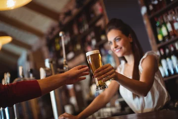 Poster Female bar tender giving glass of beer to customer © wavebreak3