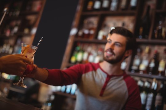 Female bar tender giving glass of cocktail to customer