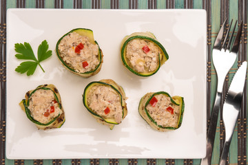 Grilled zucchini rolls with curd cheese and tuna on plate.