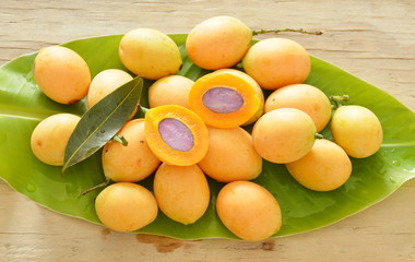 Naklejka na ściany i meble Marian plum tropical fruit produced in summer half cut on banana leaf 