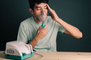 Portrait of man using domestic inhaler / nebulizer with sinusitis symptoms