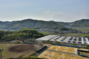 Naklejka premium 試合中の野球場とテニスコートと田園地帯