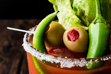 Bloody Mary Cocktail with green olive, pepper, lettuce, salt and ice.
