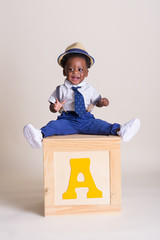 Happy one year old boy sitting on a box 