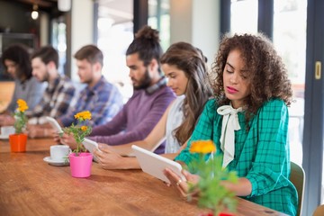 Row of young people using digital tablets