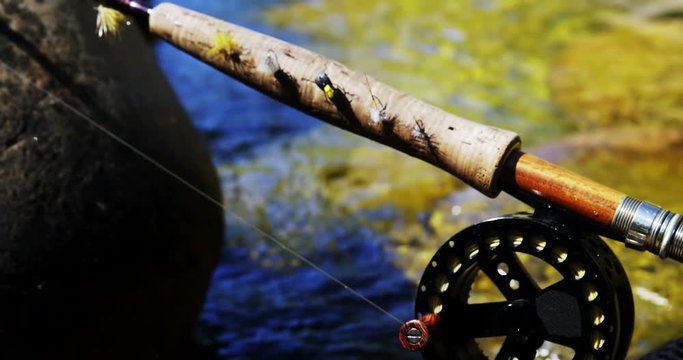 Fly fishing rod, reel and hook on rock