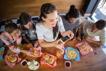 Woman with friends photographing food in restaurant