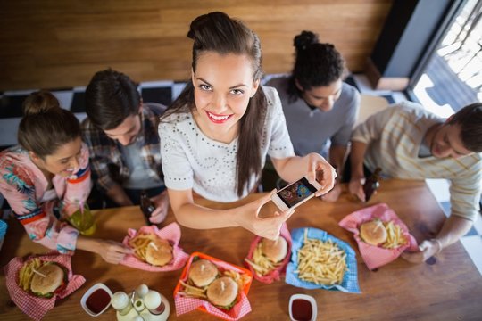 Young woman with friends photographing food in restaurant