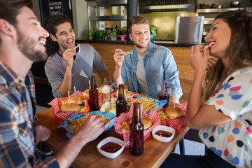 Cheerful friends eating French fries in restaurant