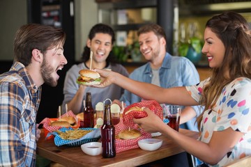 Smiling woman feeding burger to male friend 