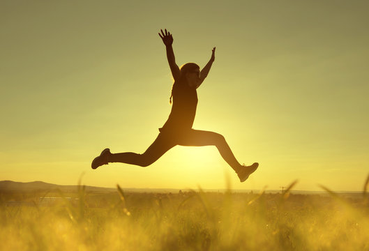 Young happiness woman jumping high at sunset.