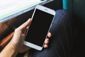 Close-up Hand holding smartphone in bus with soft-focus in the background, over light