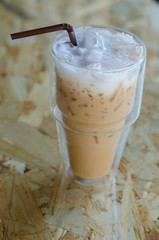 Iced coffee in a tall glass on wooden background
