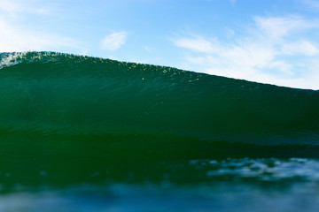 An abstract water angle of an emerald, powerful breaking wave on a bright summer day.