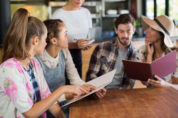 Friends discussing while giving order to waitress 