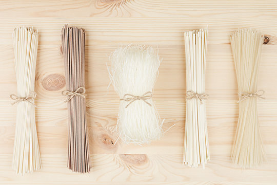 Raw asian noodles close up on beige wooden board background, top view.