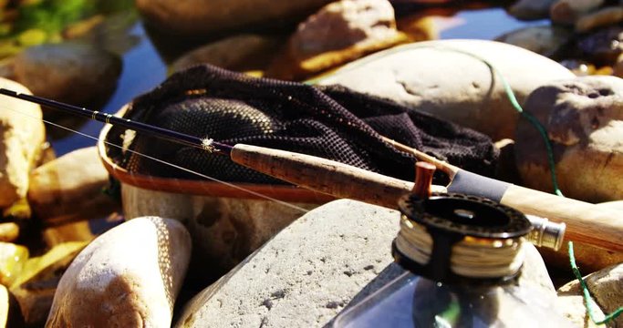 Fly fishing rod, reel and tackle box on rock