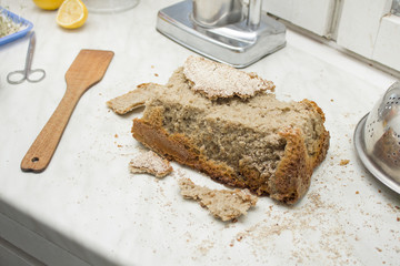 Pokruszony chleb własnego wypieku na kuchennym blacie. Nieudany wypiek domowego chleba.