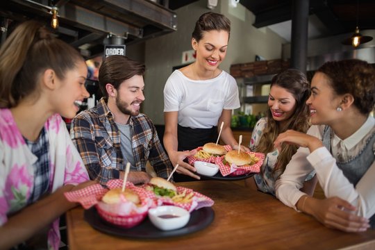 Waitress serving burgers to customers in restaurant