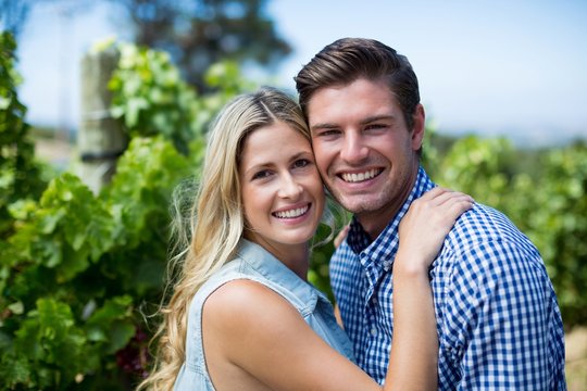 Portrait of smiling young couple hugging at vineyard