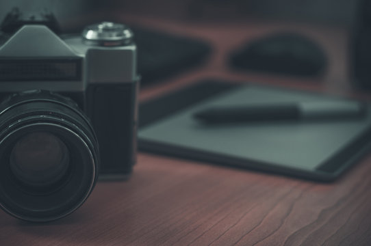 Still life of photographer desk in home office interior. Professional photo media working equipment, camera body, lenses, monitor and tablet