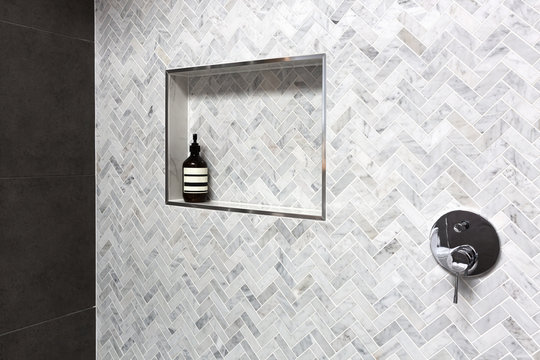 Show shelf detail in wall of herringbone marble tiles